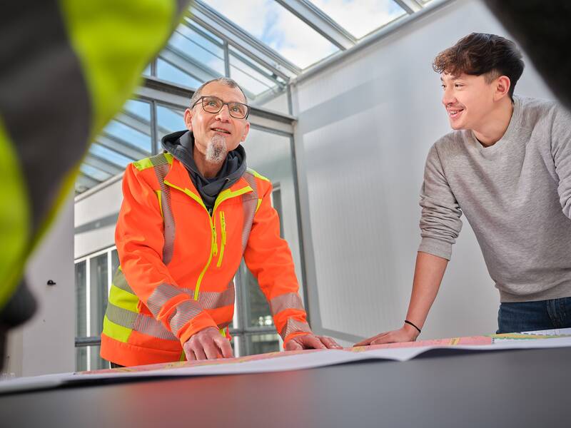 Zwei Männer stehen gebeugt über einem Stadtplan.