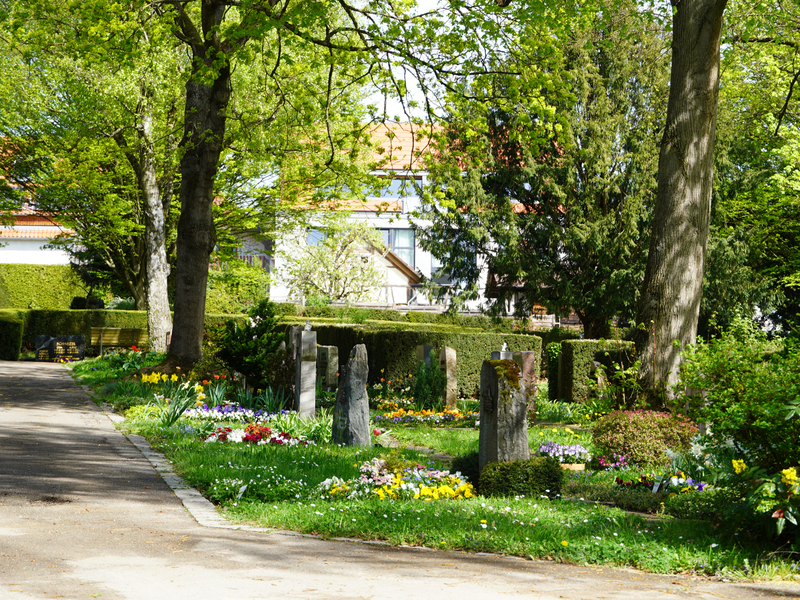 Zu sehen ist ein Friedhof mit mit bunten Blumen geschmückten Gräbern.