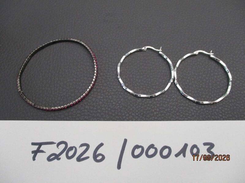Auf dem Bild sind ein schmales Armband und ein Paar silberfarbene Creolen auf einer schwarzen Oberfläche zu sehen.