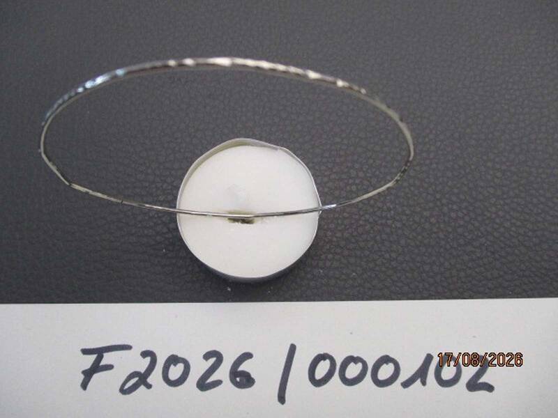 Ein silberner Armreif liegt auf einer dunklen Oberfläche, daneben ist die Aufschrift "F2026 / 000102" zu sehen.