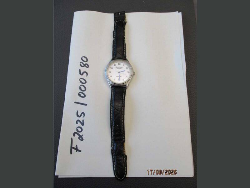 Eine Armbanduhr mit schwarzem Band, das etwas zerschlissen ist, liegt vor einem weißen Hintergrund. Die Bezeichnung F2025 000580 ist zu lesen.