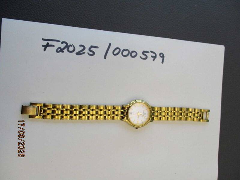 Eine goldene Armbanduhr mit metallischem Armband liegt auf einem Papier mit der handschriftlichen Notiz "F2025/000579". KI-BildBeschreiber