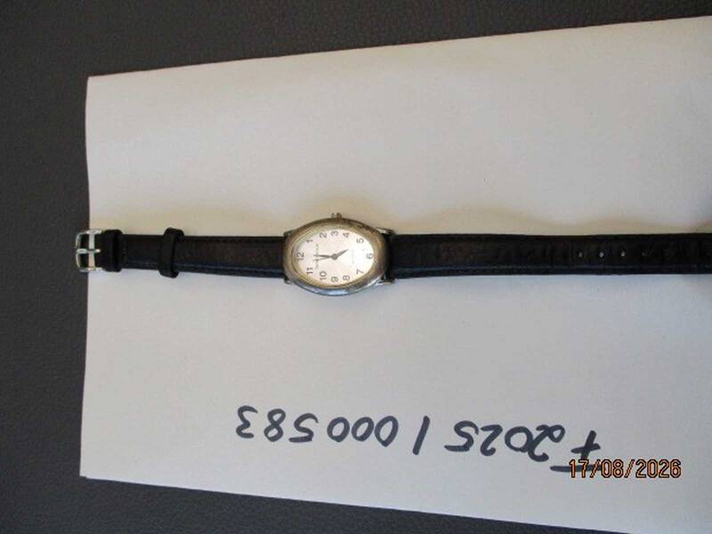 Eine Armbanduhr mit schwarzem Lederarmband liegt auf einem Blatt Papier, auf dem eine Nummer in schwarzer Schrift steht. KI-BildBeschreiber