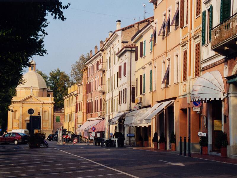 Eine ruhige Stadtstraße mit farbenfrohen Gebäuden und einer kleinen Kirche im Hintergrund.