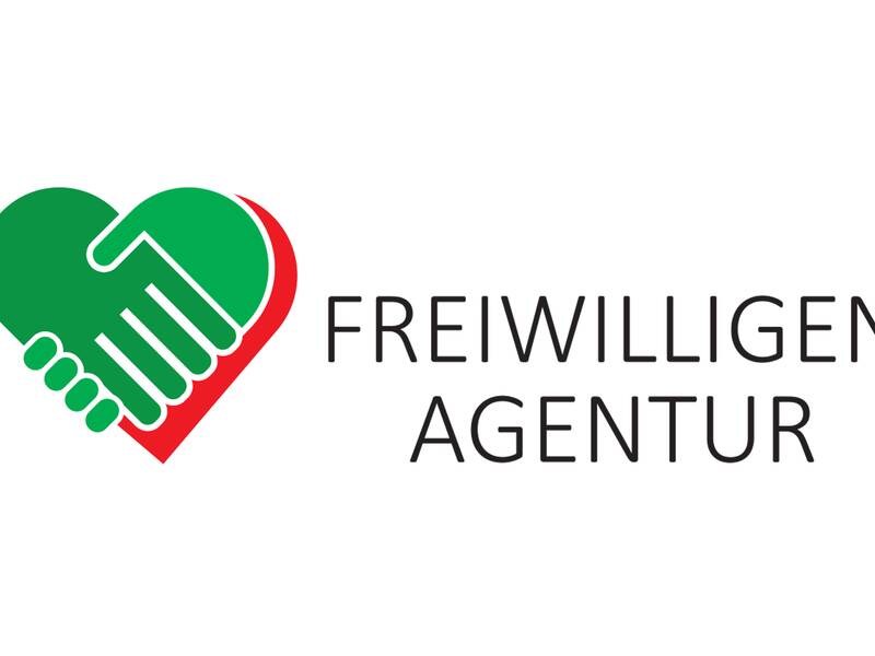 Ein Logo zeigt zwei ineinandergreifende Hände in Herzform, begleitet von der Aufschrift "Freiwilligenagentur".