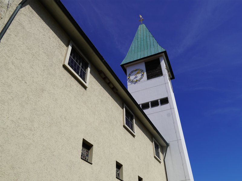 Das Foto zeigt einen weiß gestrichenen Kirchturm mit blauem Dach. 