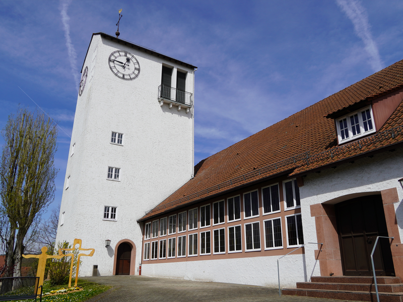 Das Foto zeigt den großen Kirchturm und den Hof der Evangelischen Kirche Scharnhausen. 