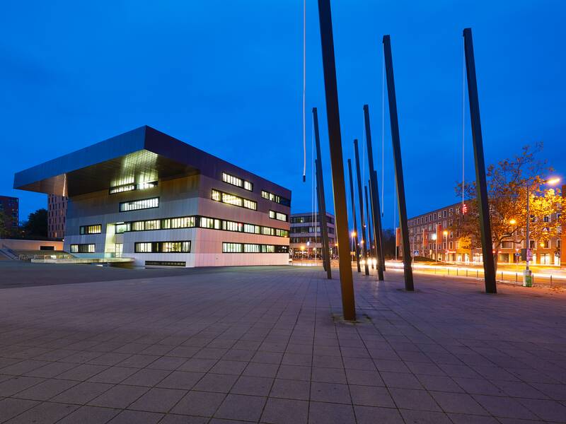 Das Stadthaus im Scharnhauser Park ist ein modernes Gebäude auf einem großen Platz, der als gestalterisches Element über einige Säulen mit Lichtkabeln verfügt. Zu sehen ist es hier in der Abenddämmerung.
