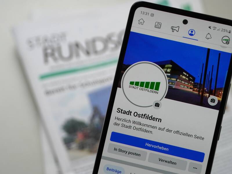 Ein Smartphone zeigt die Facebook-Seite der Stadt Ostfildern vor einem unscharfen Hintergrund mit der Stadtrundschau Ostfildern.