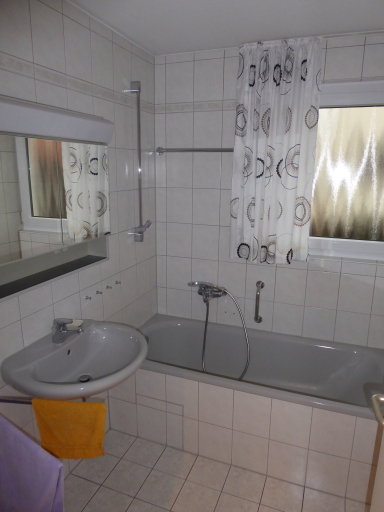 Das Tageslichtbad mit Badewanne im Erdgeschoss ist hell gefliest.