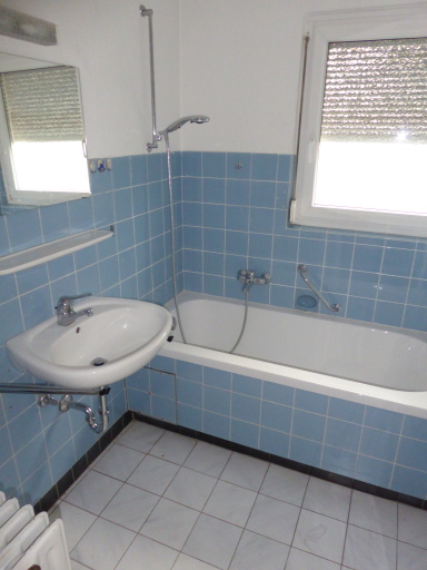 Das Tageslichtbad im ersten Obergeschoss ist hellblau gefliest und verfügt über eine Badewanne.